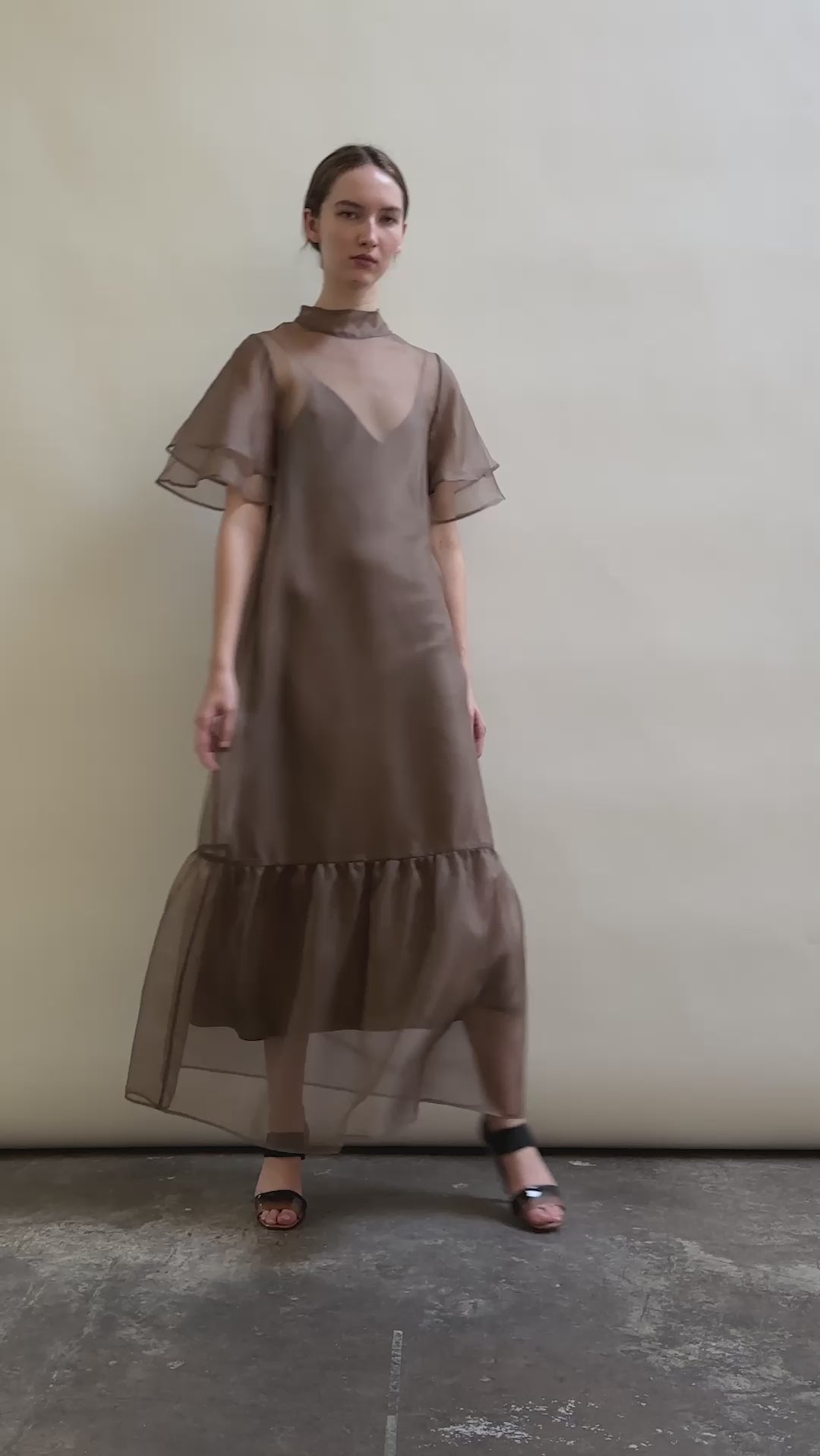 Model in a voluminous mushroom silk organza Barre maxi dress with oversized ruffles and tiered sleeves.