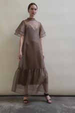 Model in a voluminous mushroom silk organza Barre maxi dress with oversized ruffles and tiered sleeves.