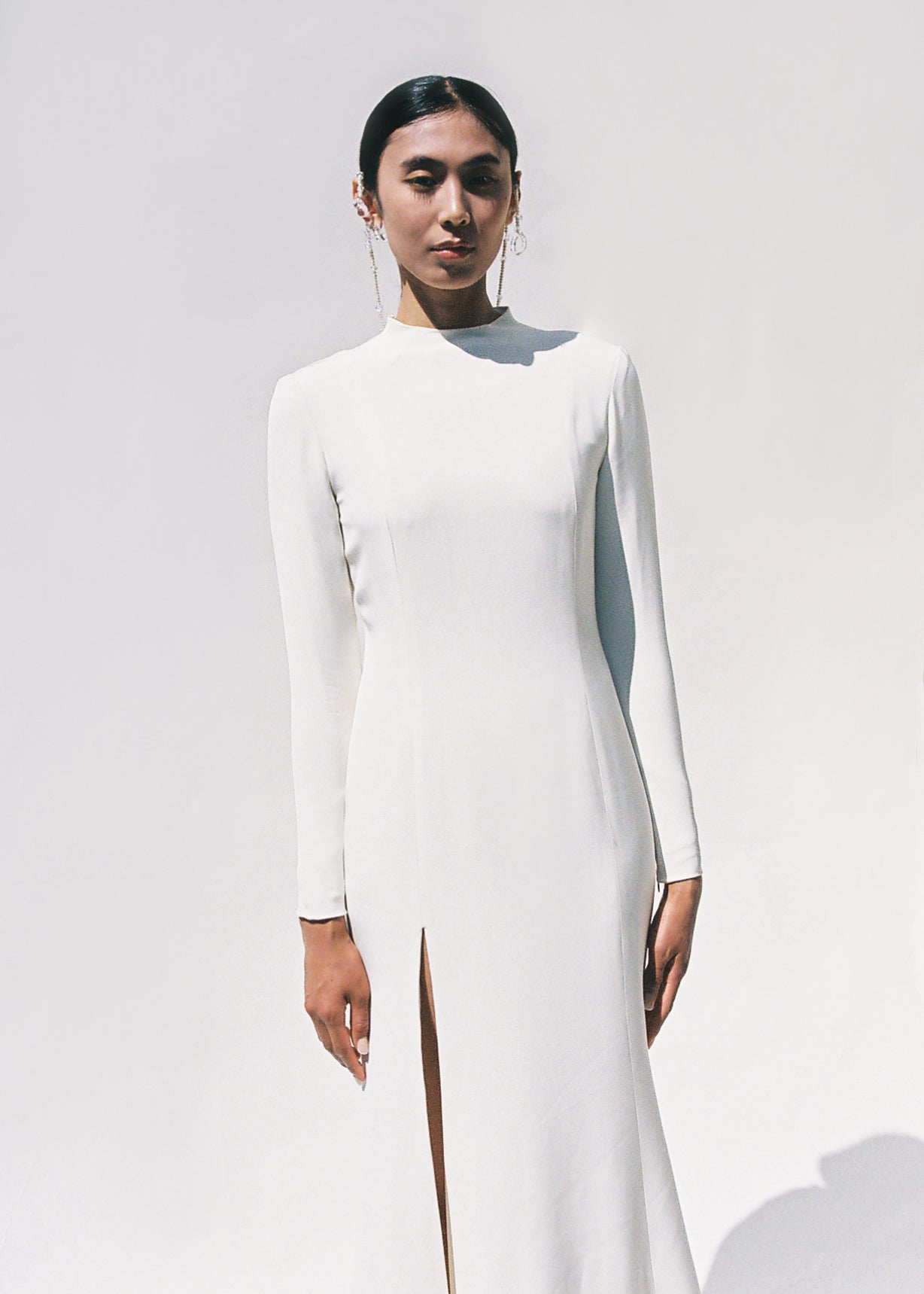 Full-length view of the Kamperett Arc Gown in Ivory silk crepe, featuring a minimalist mock neck, long tapered sleeves, and a sculptural side leg slit.