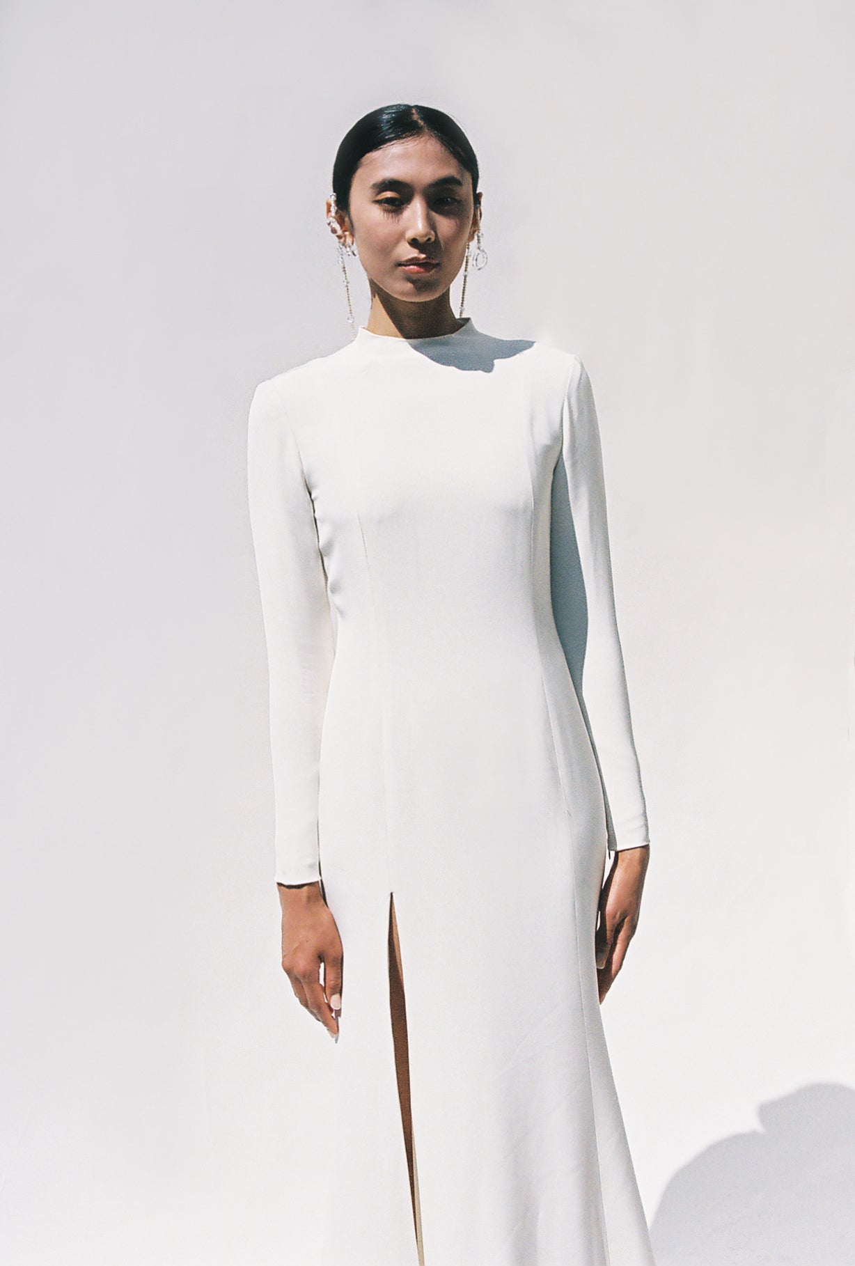 Full-length view of the Kamperett Arc Gown in Ivory silk crepe, featuring a minimalist mock neck, long tapered sleeves, and a sculptural side leg slit.