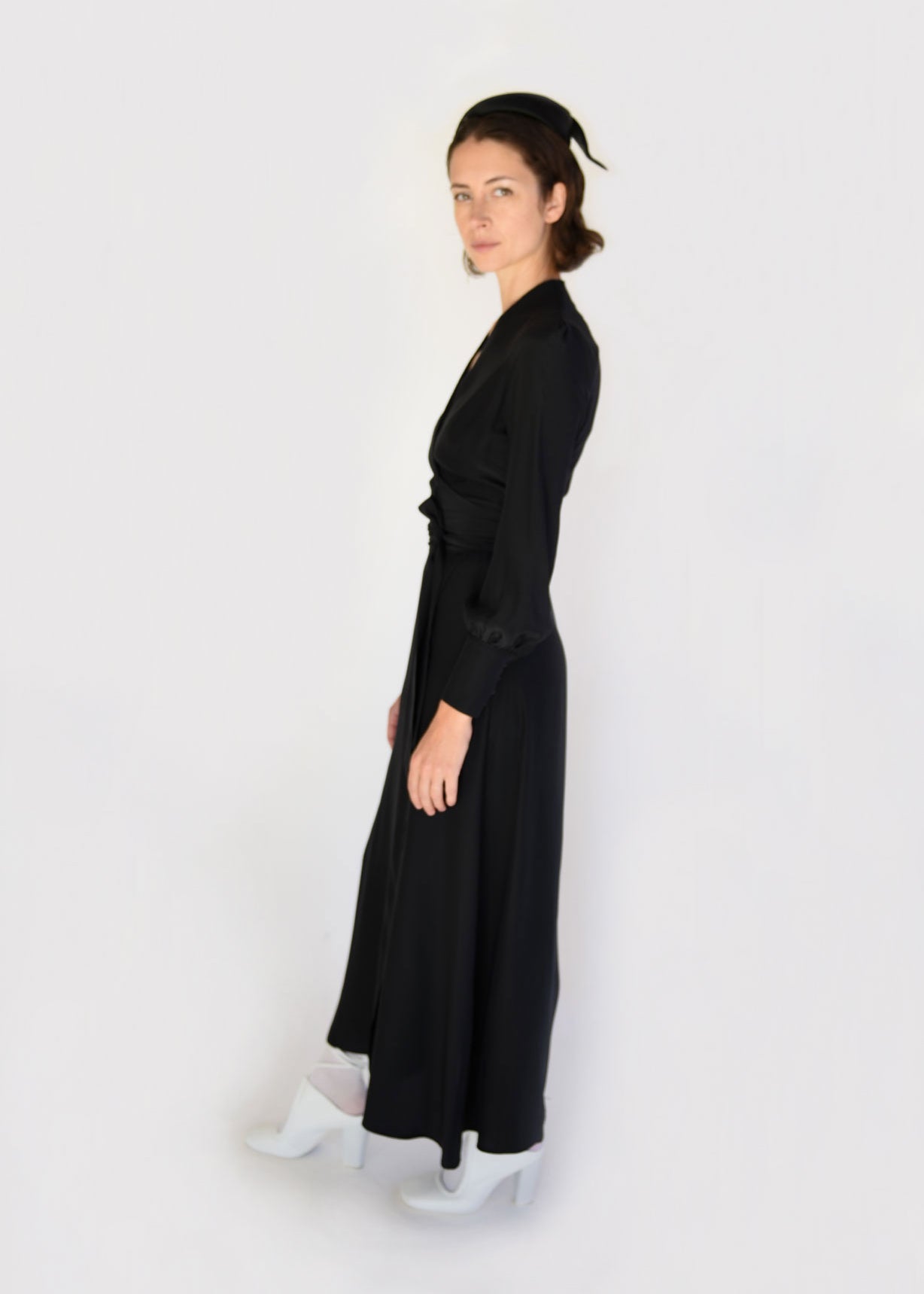 Angled view of the black matte silk charmeuse Kamperett Adelaide Midi Dress with full sleeves and self-belt.
