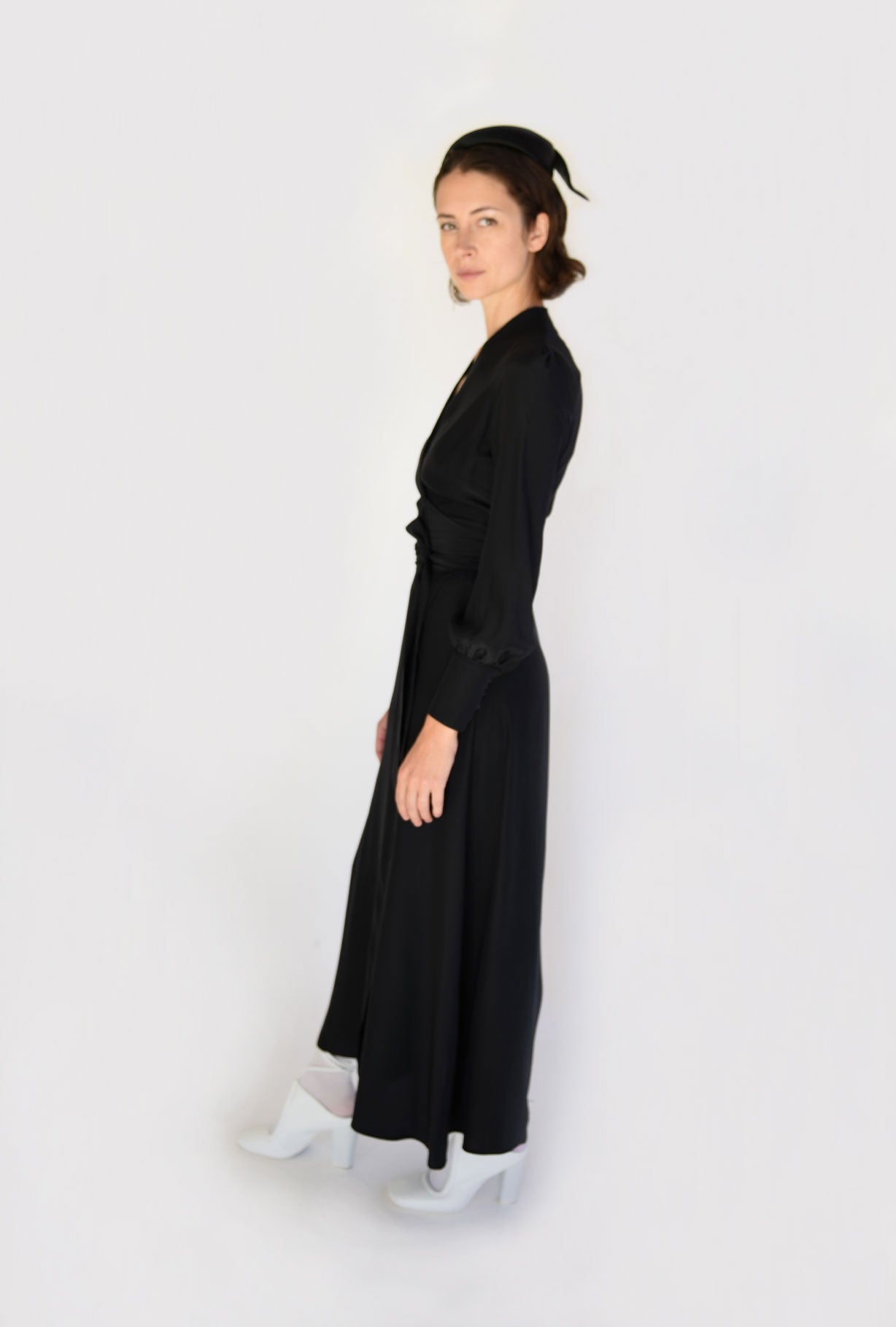 Angled view of the black matte silk charmeuse Kamperett Adelaide Midi Dress with full sleeves and self-belt.