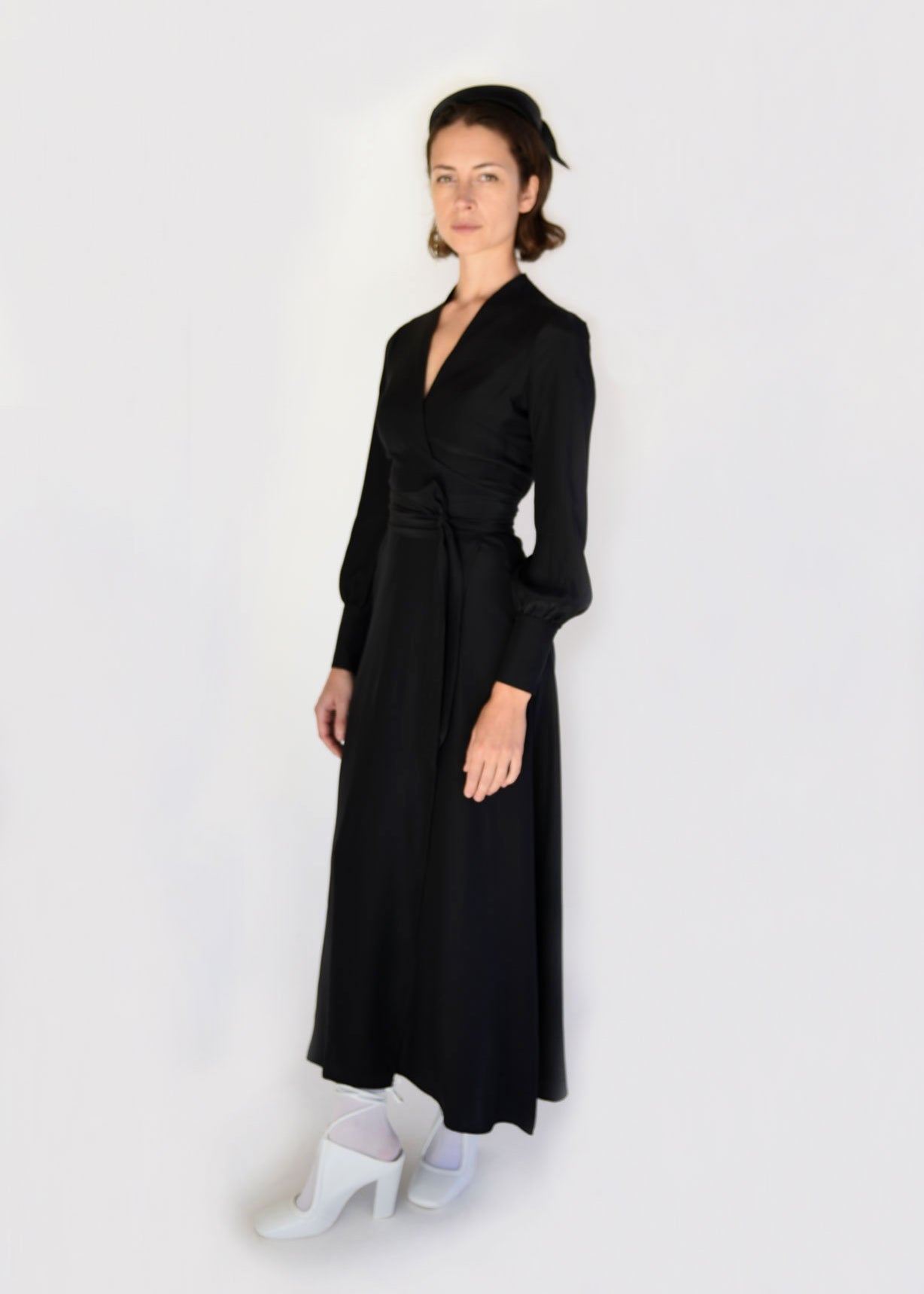 Front view of a model wearing the black matte silk charmeuse Kamperett Adelaide Midi Dress, a wrap dress with plunging neckline and full sleeves.