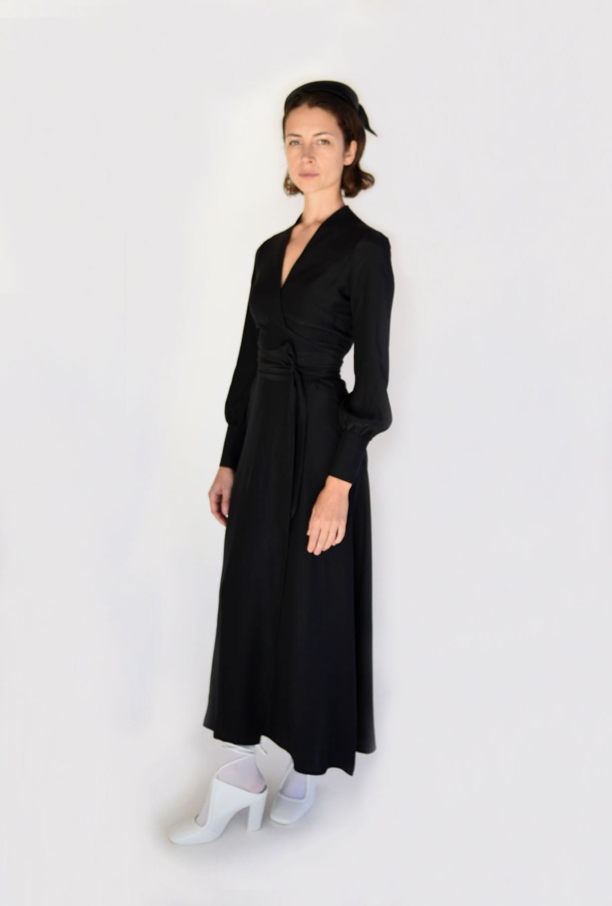 Front view of a model wearing the black matte silk charmeuse Kamperett Adelaide Midi Dress, a wrap dress with plunging neckline and full sleeves.