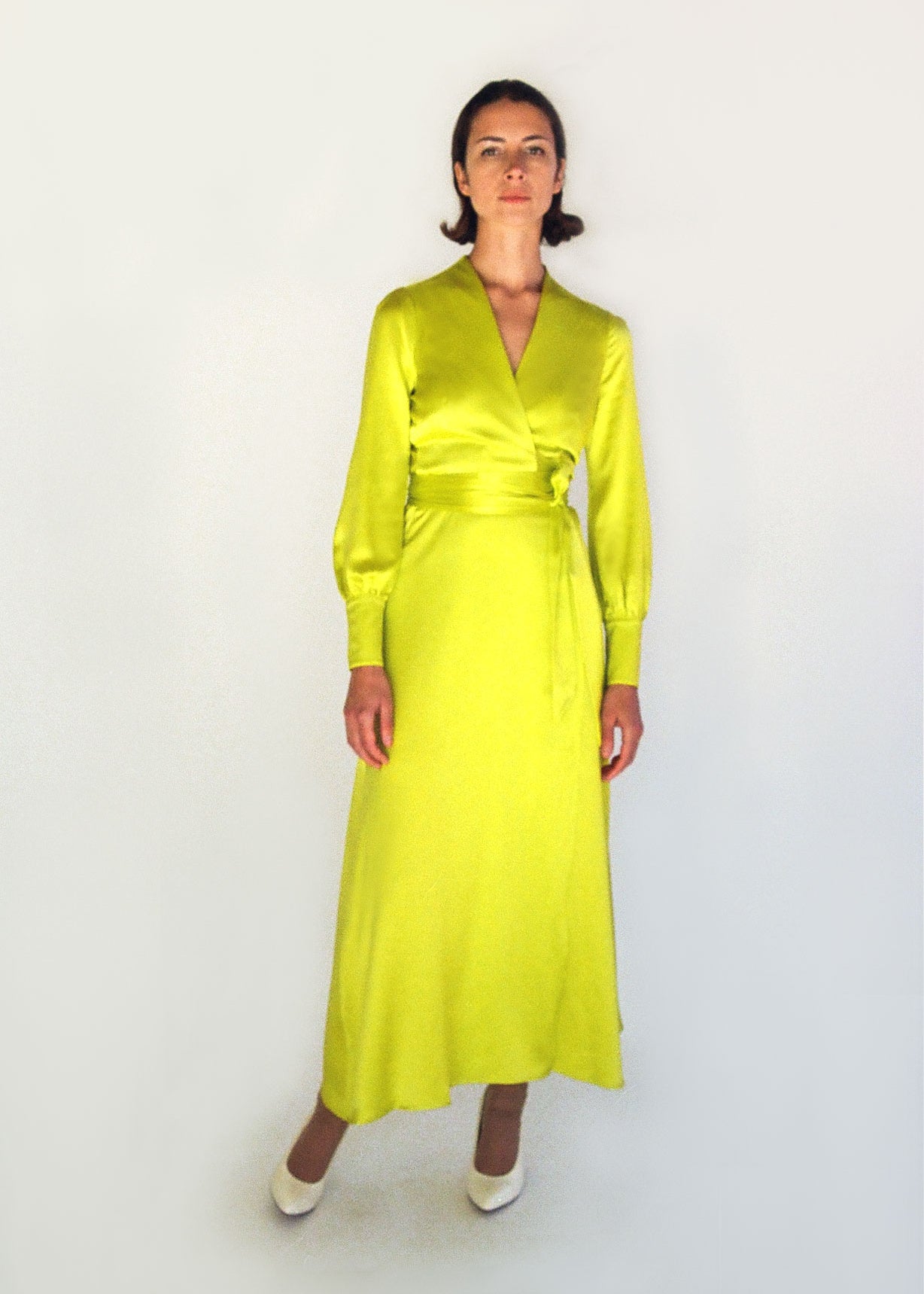 Angled view of the chartreuse satin silk charmeuse Kamperett Adelaide Midi Dress showing the fluid wrap drape.