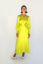 Angled view of the chartreuse satin silk charmeuse Kamperett Adelaide Midi Dress showing the fluid wrap drape.