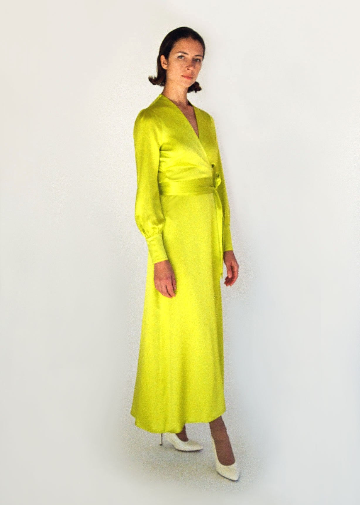 Front view of a model wearing the chartreuse satin silk charmeuse Kamperett Adelaide Midi Dress, a wrap dress with plunging neckline and full sleeves.