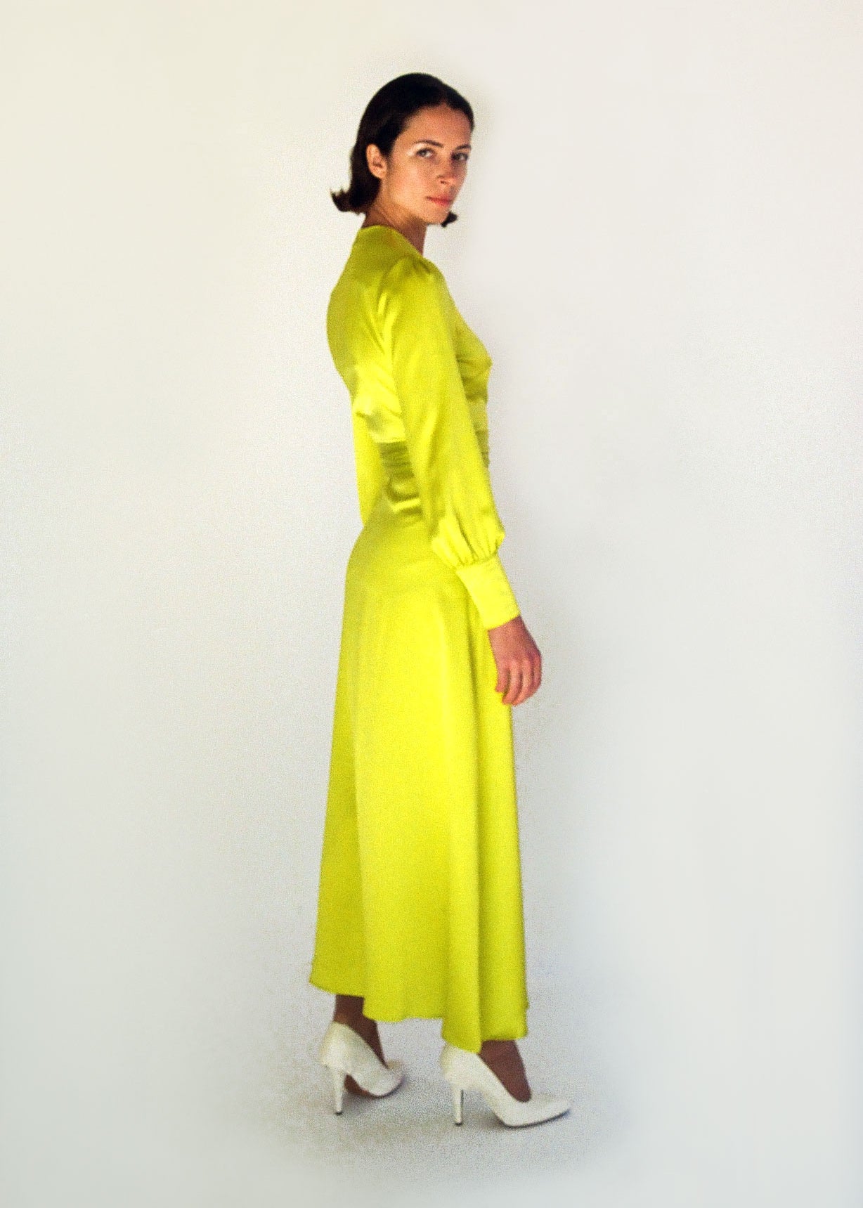 Side view of the chartreuse satin silk charmeuse Kamperett Adelaide Midi Dress with full sleeves and self-belt at the natural waist.