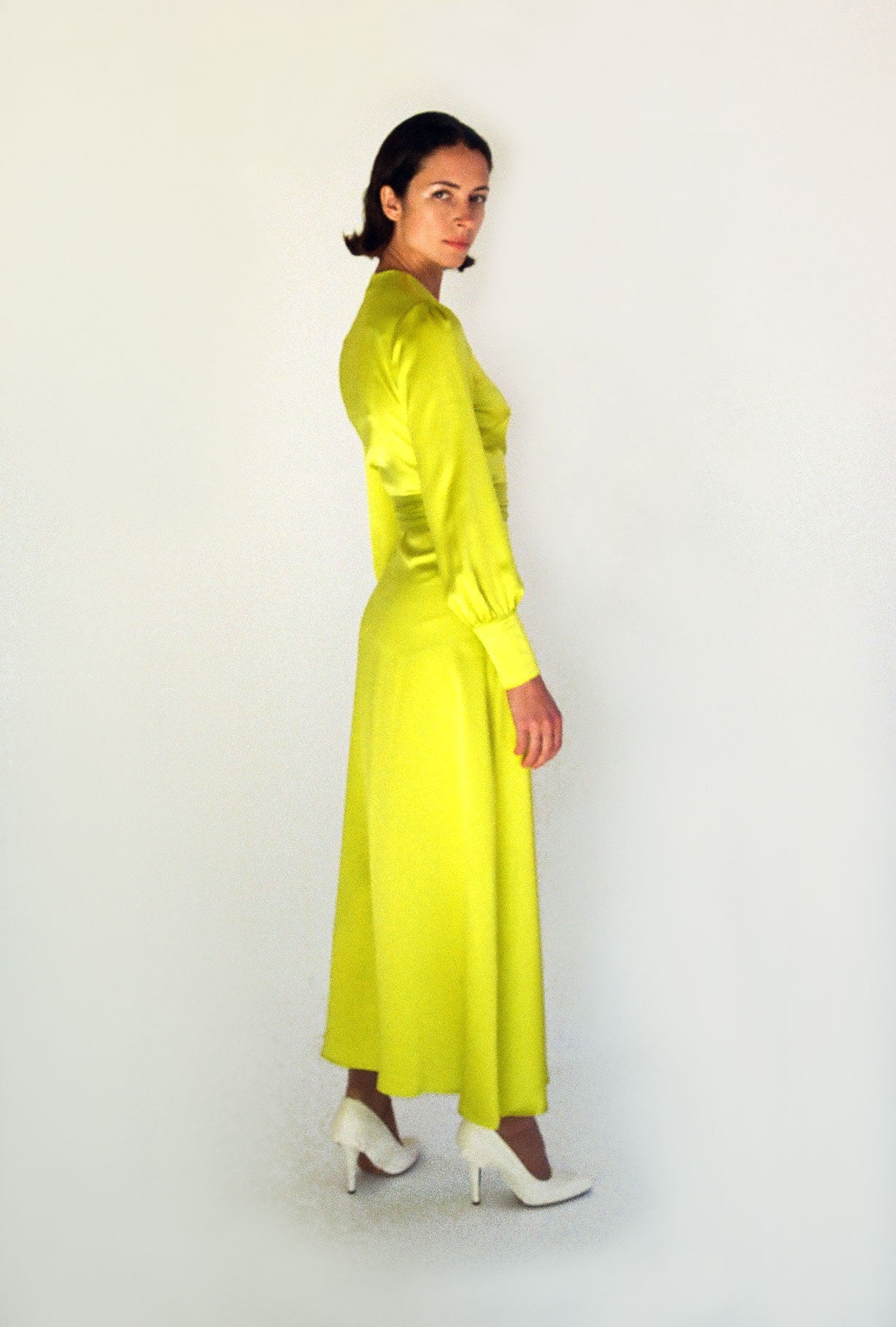 Side view of the chartreuse satin silk charmeuse Kamperett Adelaide Midi Dress with full sleeves and self-belt at the natural waist.