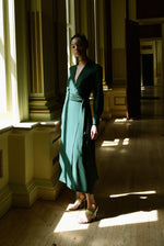 Angled view of the dark green matte silk charmeuse Kamperett Adelaide Midi Dress showing the wrap closure.