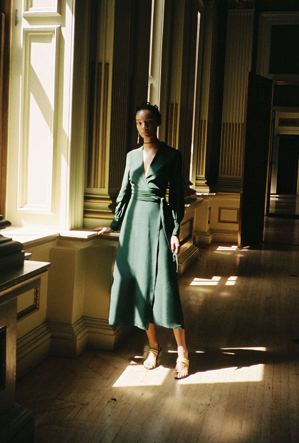 Front view of a model wearing the dark green matte silk charmeuse Kamperett Adelaide Midi Dress, a wrap dress with plunging neckline and full sleeves.