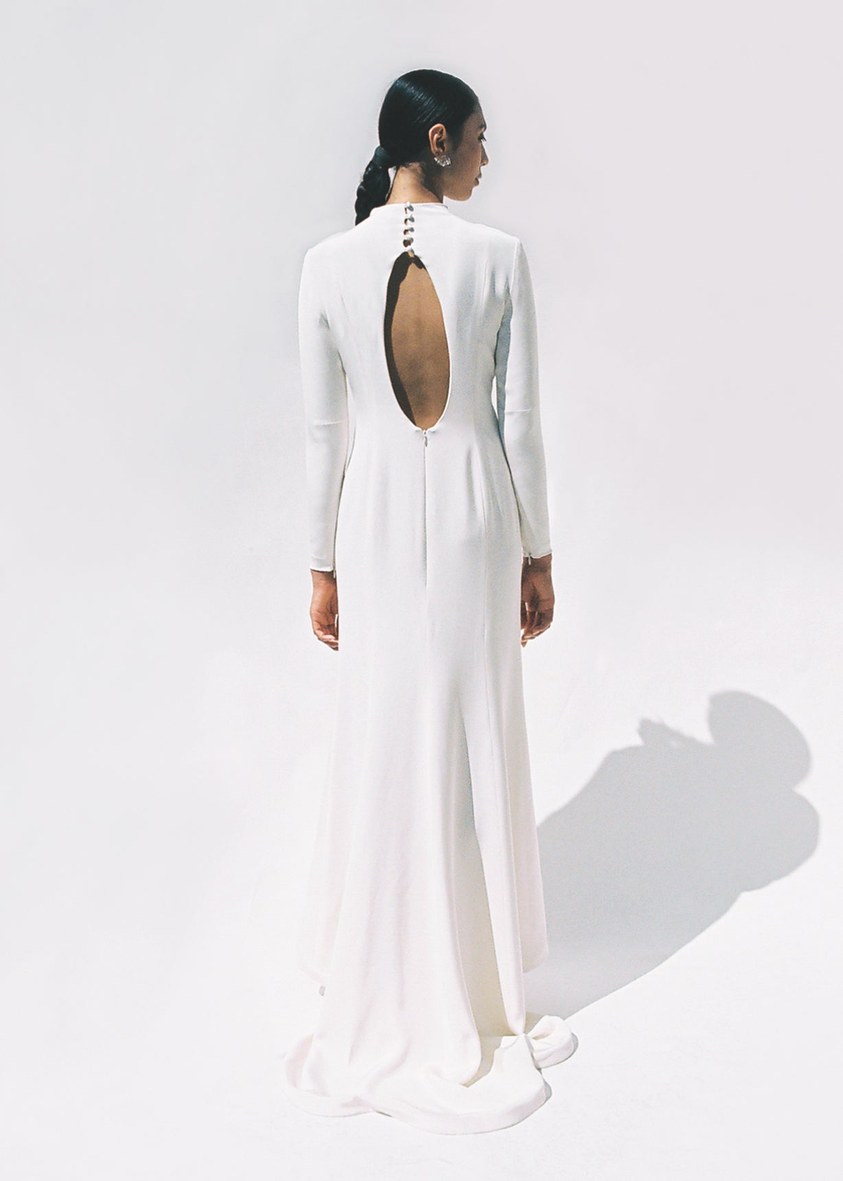 Full-length view of the Kamperett Arc Gown in Ivory silk crepe, featuring a minimalist mock neck, long tapered sleeves, and a sculptural side leg slit.