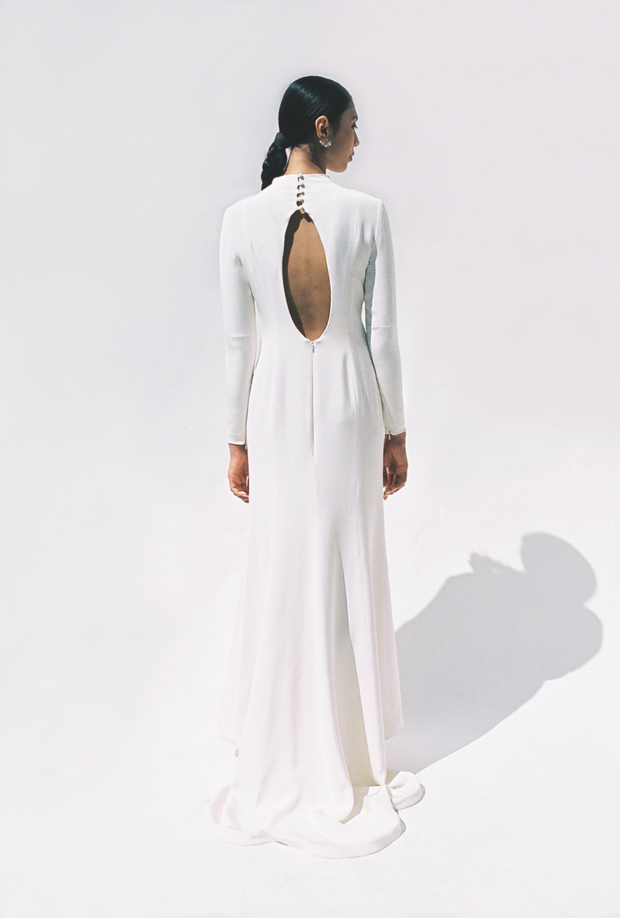 Full-length view of the Kamperett Arc Gown in Ivory silk crepe, featuring a minimalist mock neck, long tapered sleeves, and a sculptural side leg slit.