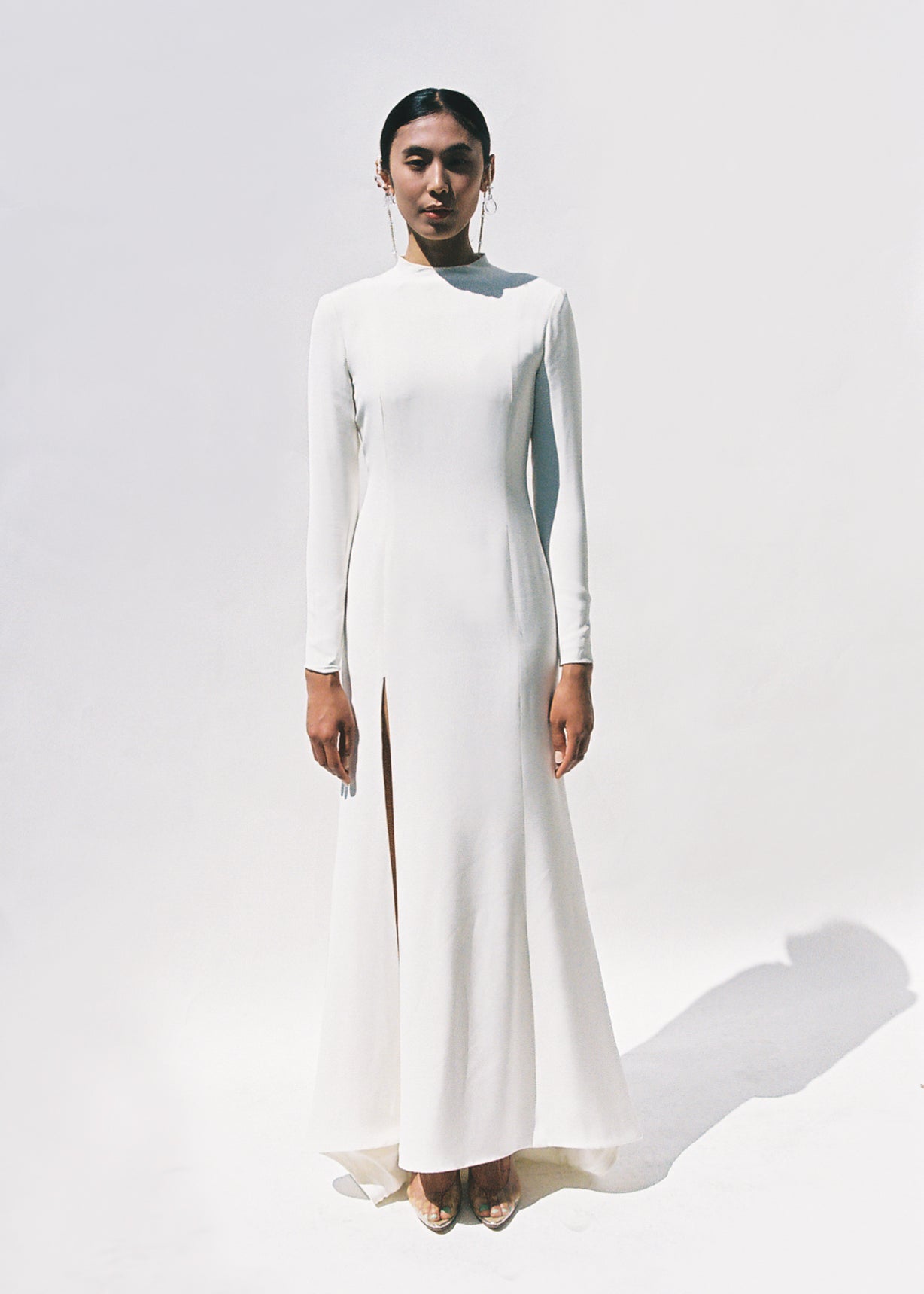 Full-length view of the Kamperett Arc Gown in Ivory silk crepe, featuring a minimalist mock neck, long tapered sleeves, and a sculptural side leg slit.