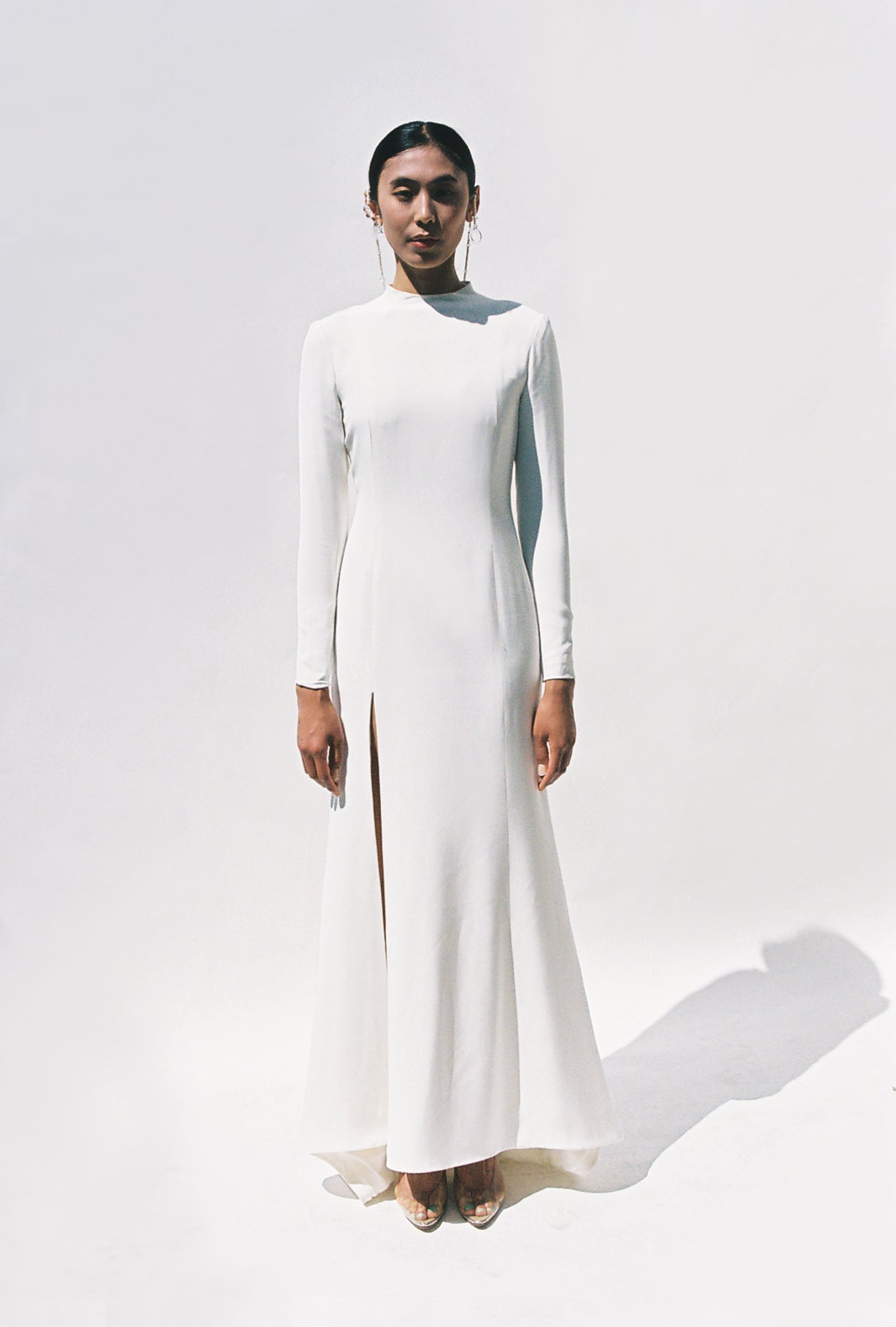Full-length view of the Kamperett Arc Gown in Ivory silk crepe, featuring a minimalist mock neck, long tapered sleeves, and a sculptural side leg slit.