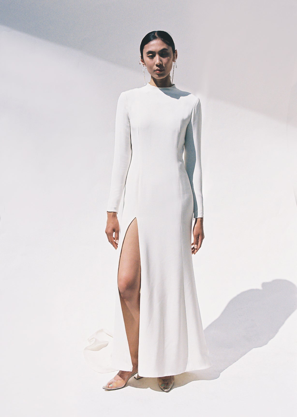 Full-length view of the Kamperett Arc Gown in Ivory silk crepe, featuring a minimalist mock neck, long tapered sleeves, and a sculptural side leg slit.