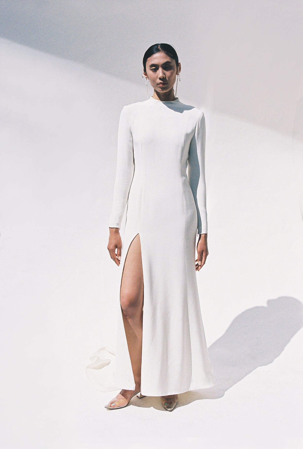 Full-length view of the Kamperett Arc Gown in Ivory silk crepe, featuring a minimalist mock neck, long tapered sleeves, and a sculptural side leg slit.