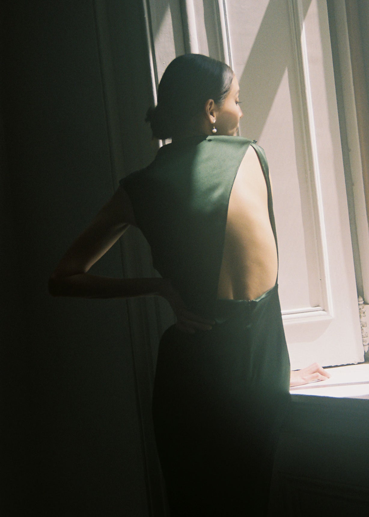 Back view of the dark green silk charmeuse Kamperett Lockwood Gown with dramatic asymmetrical back cut-out.