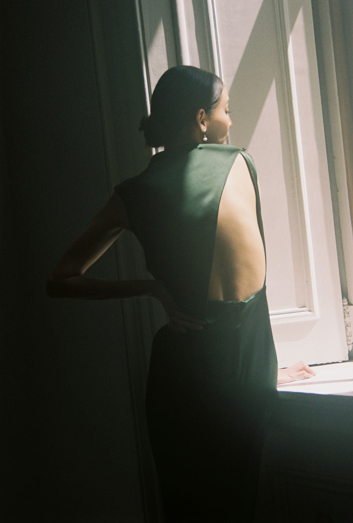 Back view of the dark green silk charmeuse Kamperett Lockwood Gown with dramatic asymmetrical back cut-out.