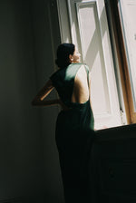 Front view of a model wearing the dark green silk charmeuse Kamperett Lockwood Gown, a sleeveless floor-length column.