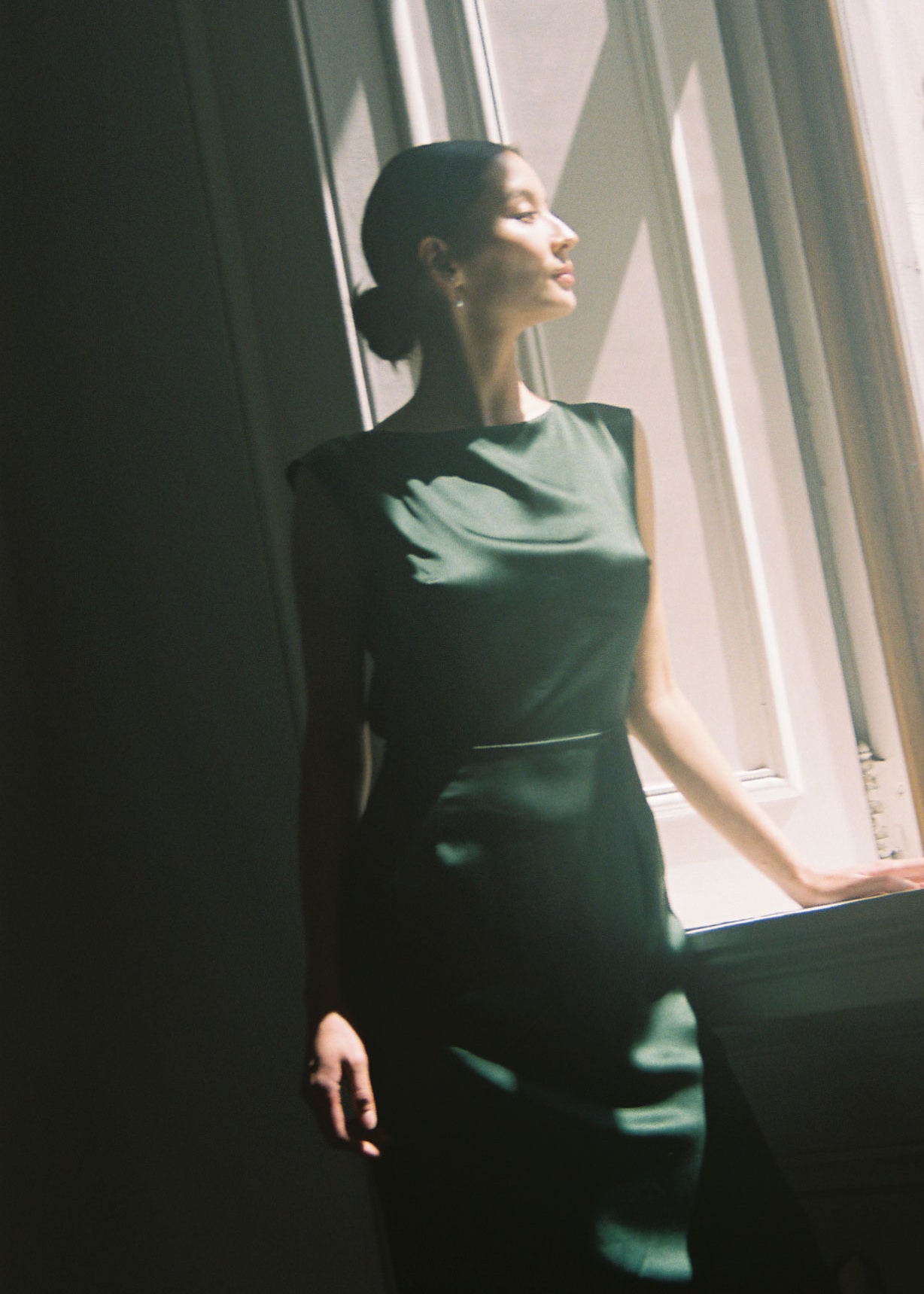 Side view of the dark green silk charmeuse Kamperett Lockwood Gown showing the deep side slit.