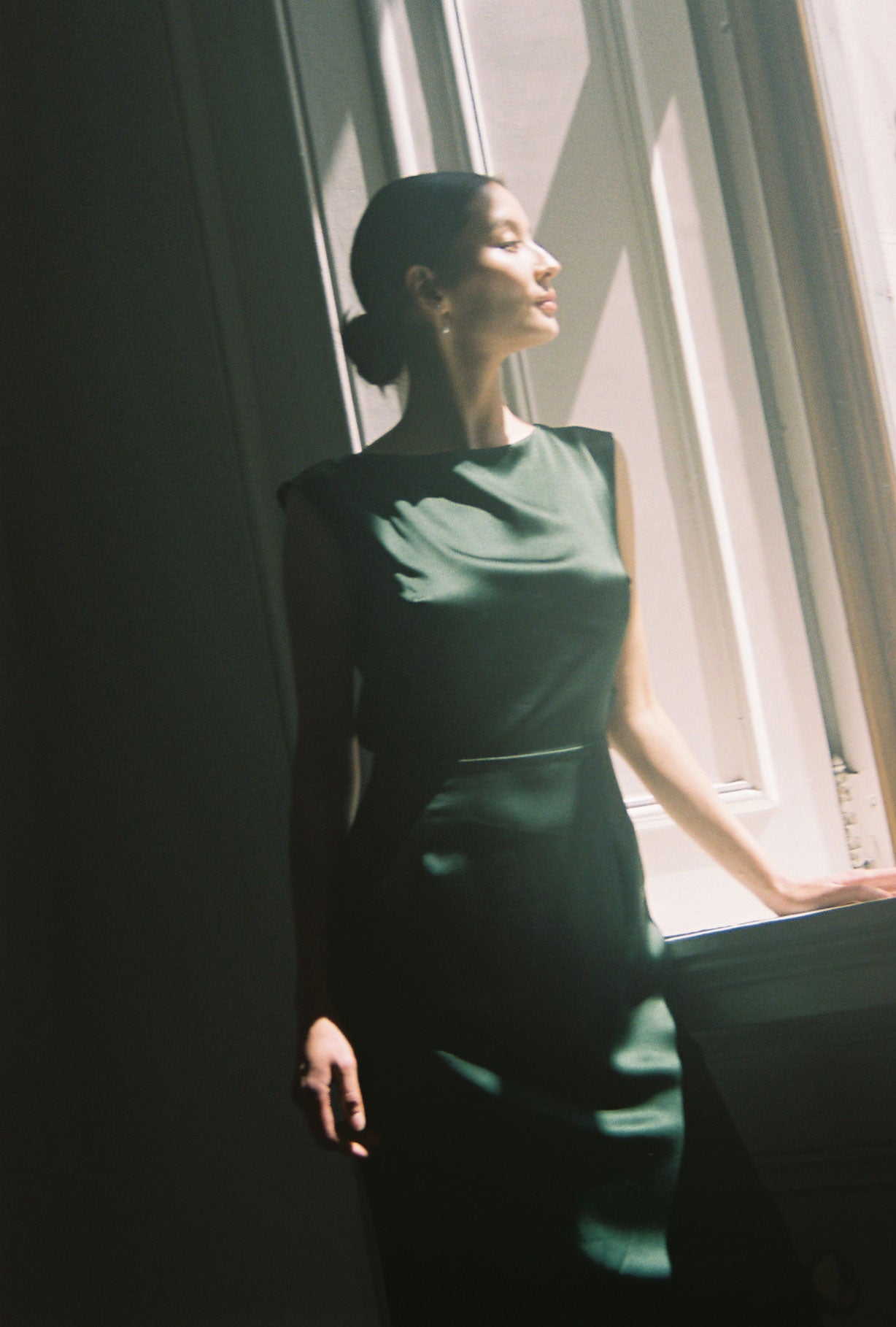 Side view of the dark green silk charmeuse Kamperett Lockwood Gown showing the deep side slit.