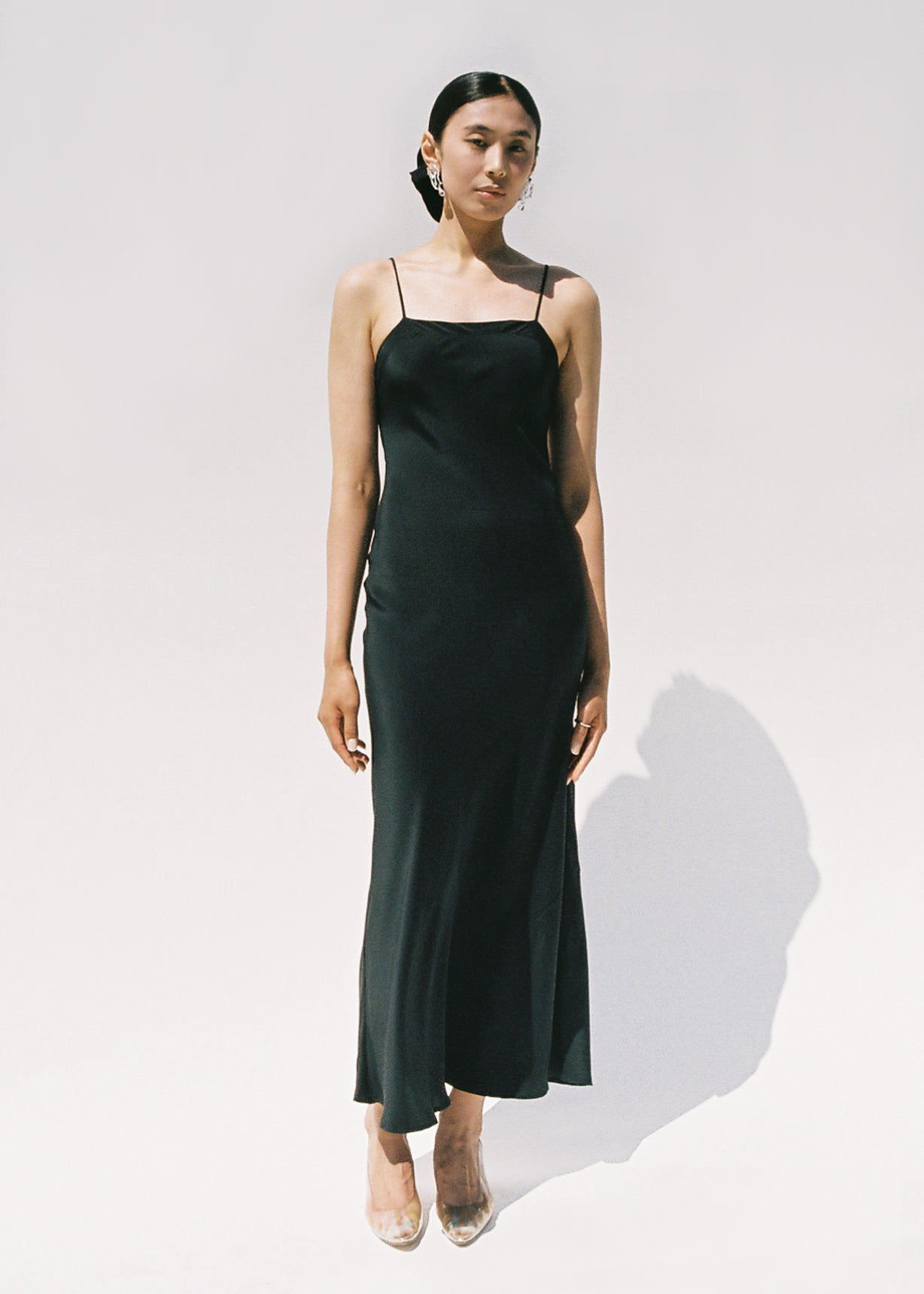 Front view of a model wearing the black matte silk charmeuse Kamperett Long Slip, a bias-cut maxi with straight neckline.