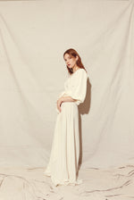 Front view of a bride wearing the alabaster four-ply silk crepe Kamperett Loretta Gown, a maxi wrap with billowing short sleeves.