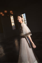 Front view of a bride wearing the ivory silk organza Kamperett Loretta Midi wedding dress, a wrap with elbow-length sleeves and shoulder ruffle.