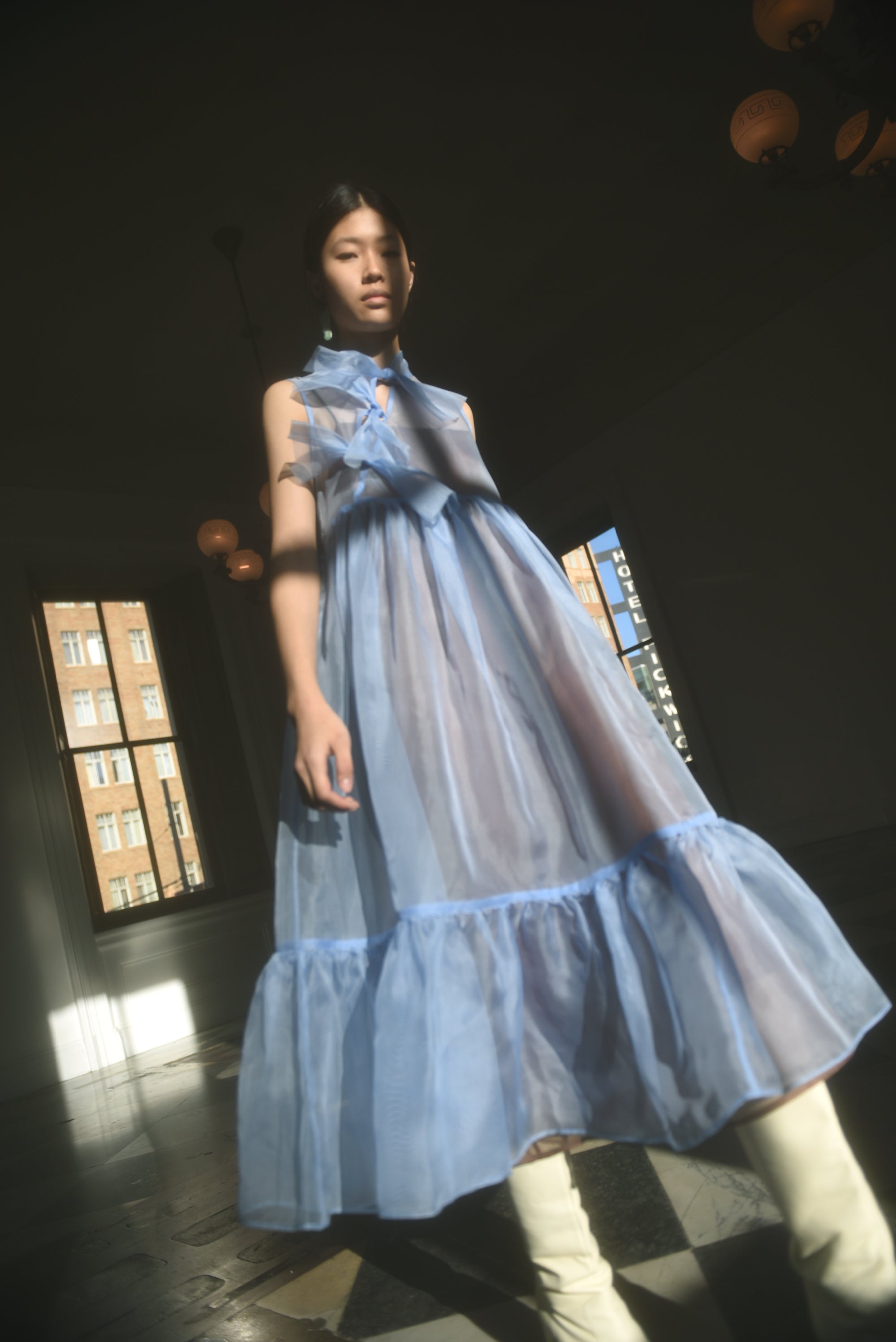 Front view of a model wearing the cornflower silk organza Kamperett Mae Dress, a midi with empire waist and qipao-inspired tie front.