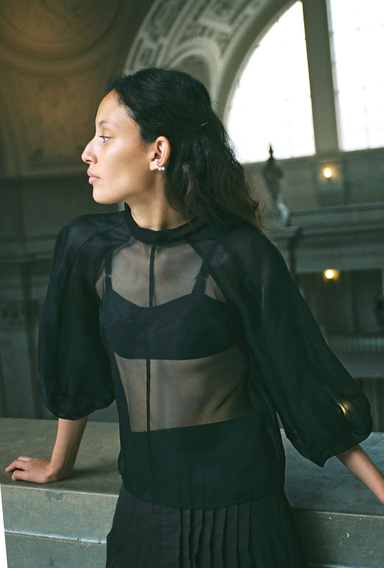 Front view of a model wearing the black silk organza Kamperett Meiere Blouse with architectural sleeves and mock neck.