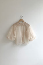 Angled view of the ivory silk organza Kamperett Meiere Blouse showing the intricately seamed cut-glass sleeves.