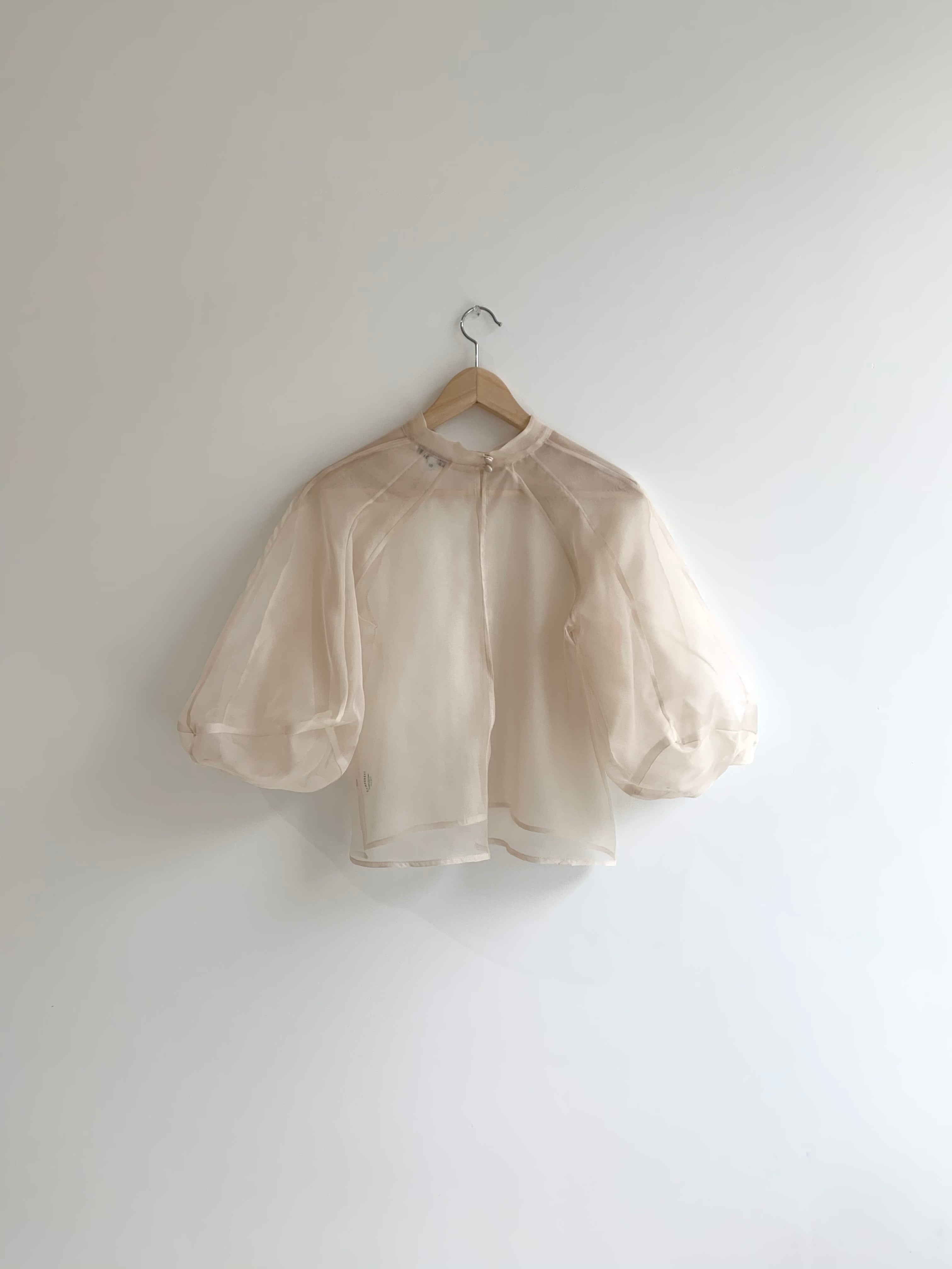 Angled view of the ivory silk organza Kamperett Meiere Blouse showing the intricately seamed cut-glass sleeves.