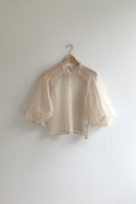 Front view of a bride wearing the ivory silk organza Kamperett Meiere Blouse with architectural sleeves and mock neck.