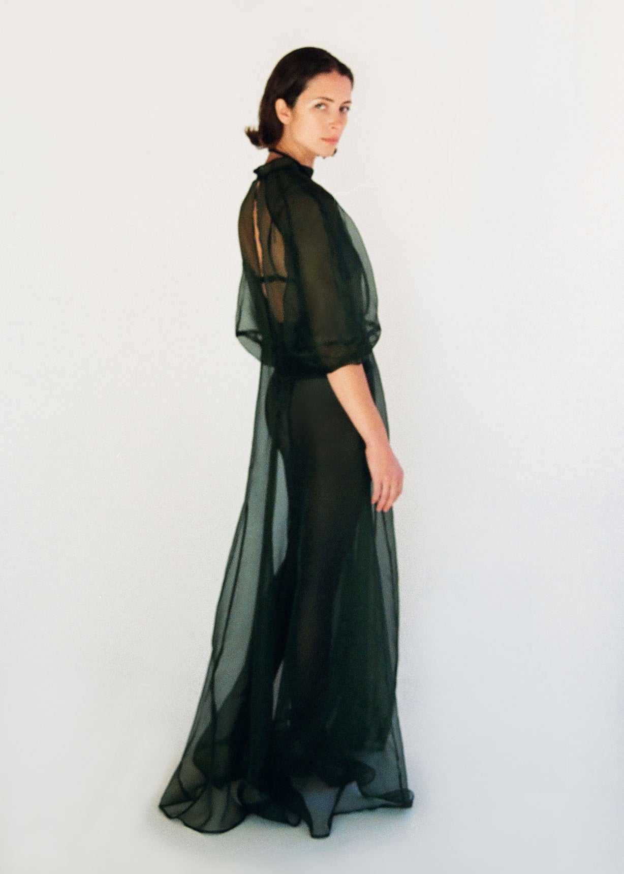 Angled view of the dark green silk organza Kamperett Meiere Gown with intricately seamed cut-glass-inspired sleeves.