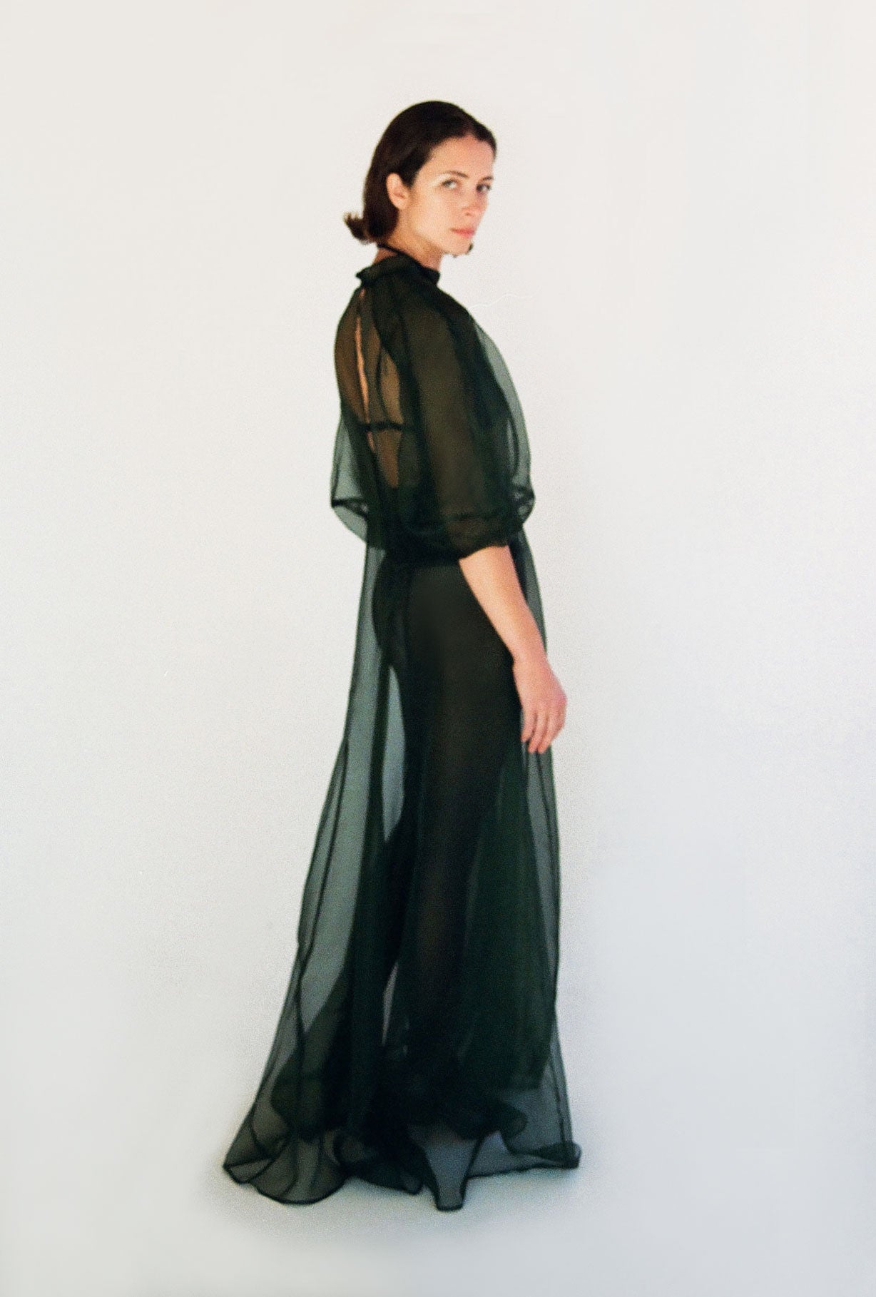 Angled view of the dark green silk organza Kamperett Meiere Gown with intricately seamed cut-glass-inspired sleeves.