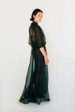 Angled view of the dark green silk organza Kamperett Meiere Gown with intricately seamed cut-glass-inspired sleeves.
