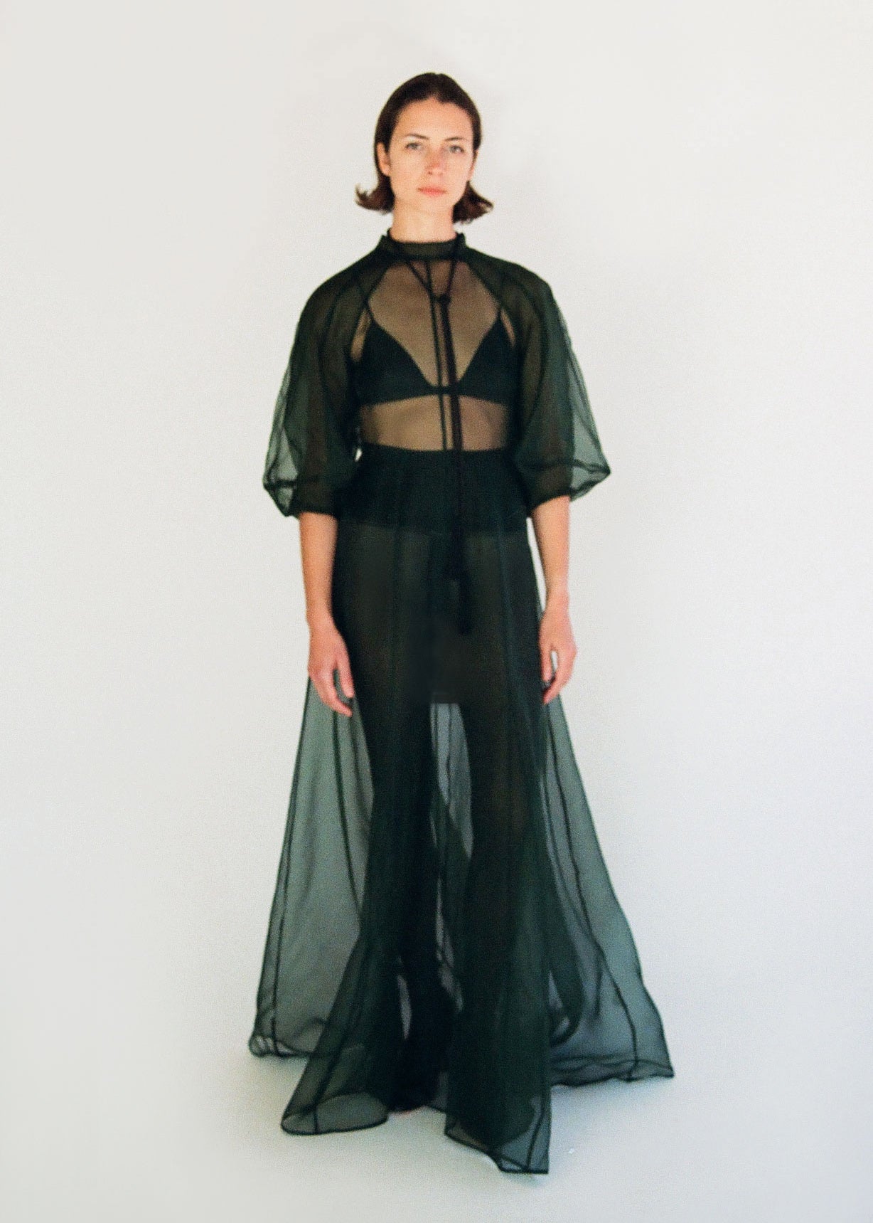 Front view of a model wearing the dark green silk organza Kamperett Meiere Gown, with architectural sleeves and fitted waist.