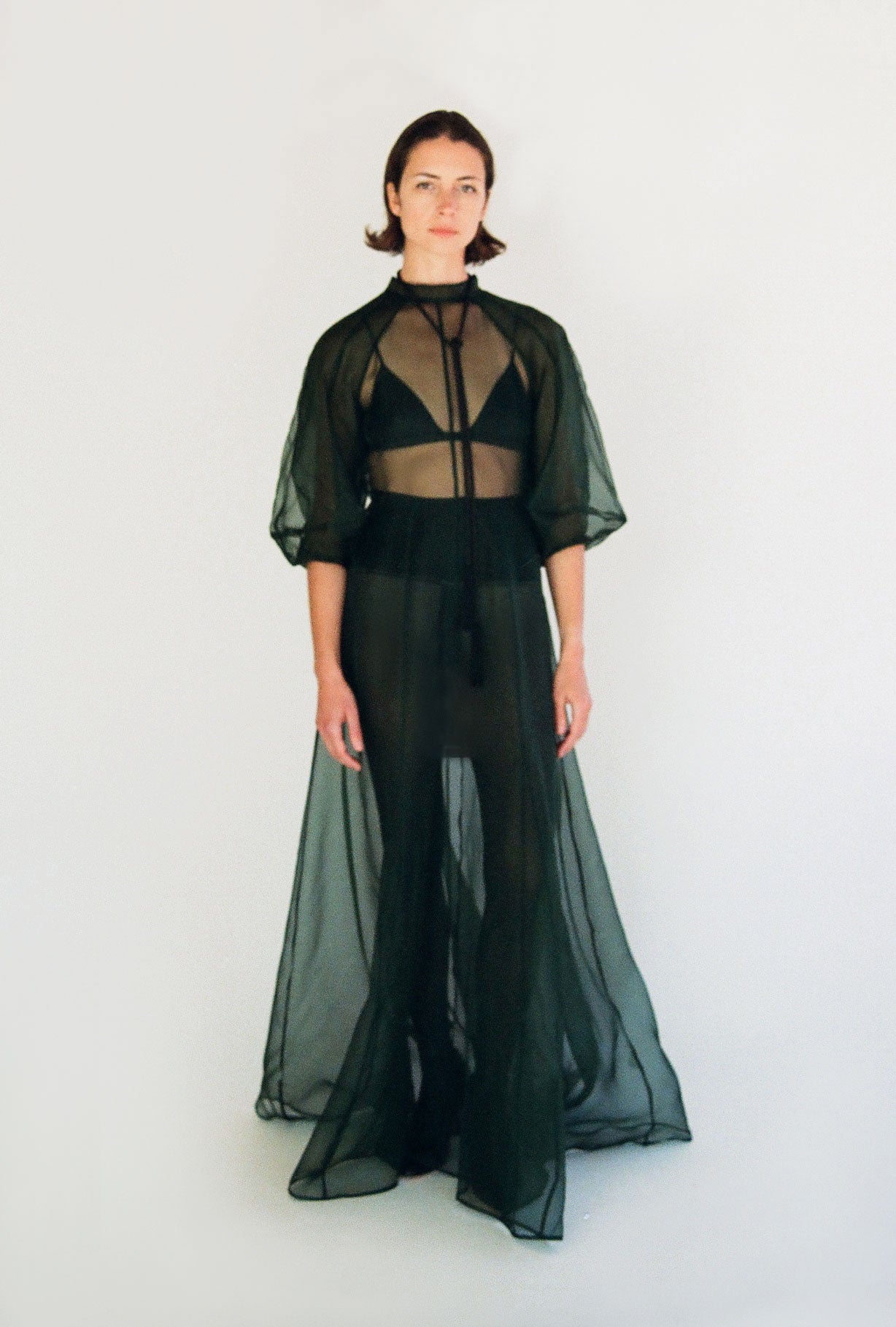 Front view of a model wearing the dark green silk organza Kamperett Meiere Gown, with architectural sleeves and fitted waist.