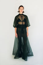 Front view of a model wearing the dark green silk organza Kamperett Meiere Gown, with architectural sleeves and fitted waist.