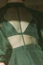 Motion shot of the dark green silk organza Kamperett Meiere Gown, capturing the sweeping multi-godet skirt.