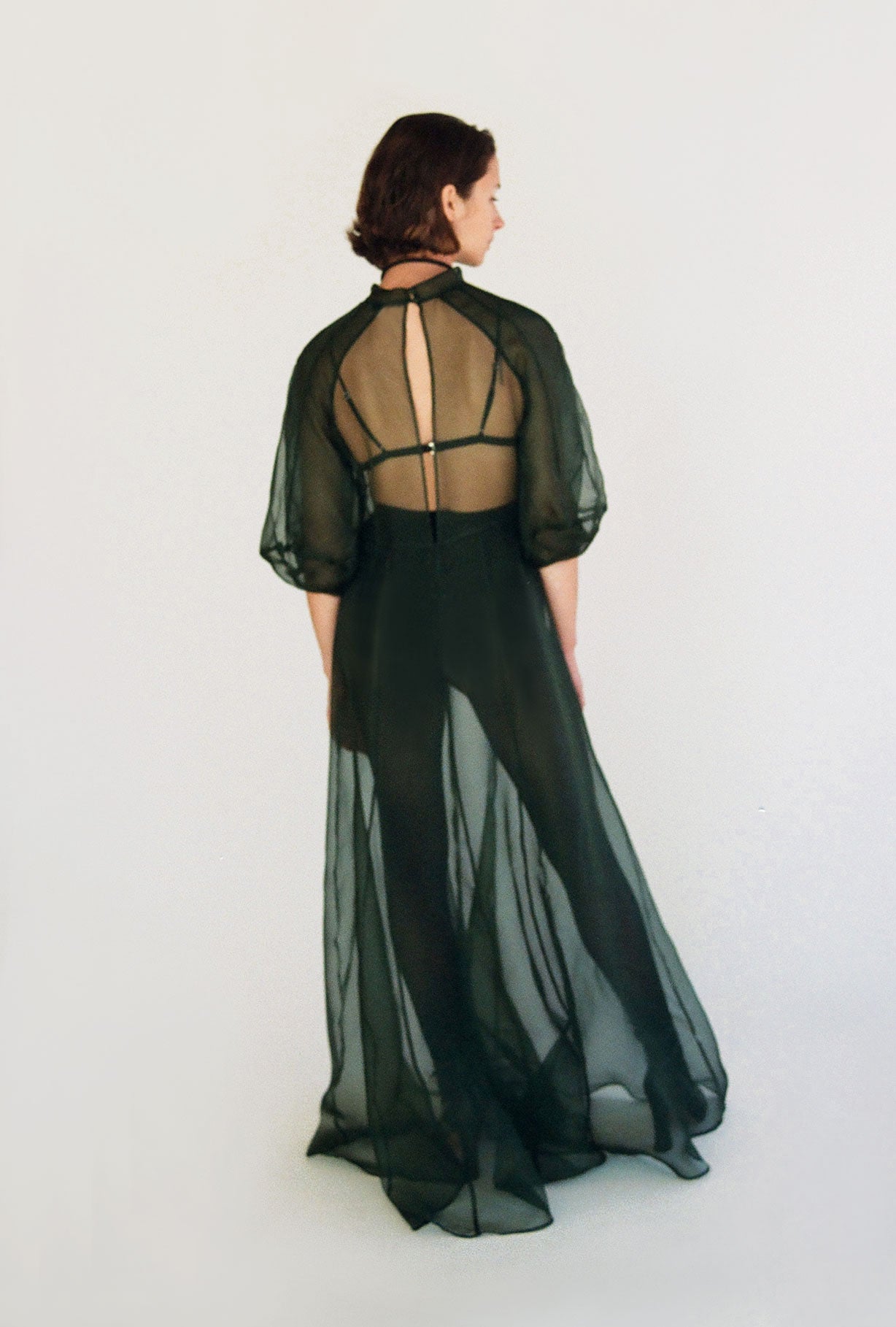 Side view of the dark green silk organza Kamperett Meiere Gown showing the multi-godet skirt opening into fullness.