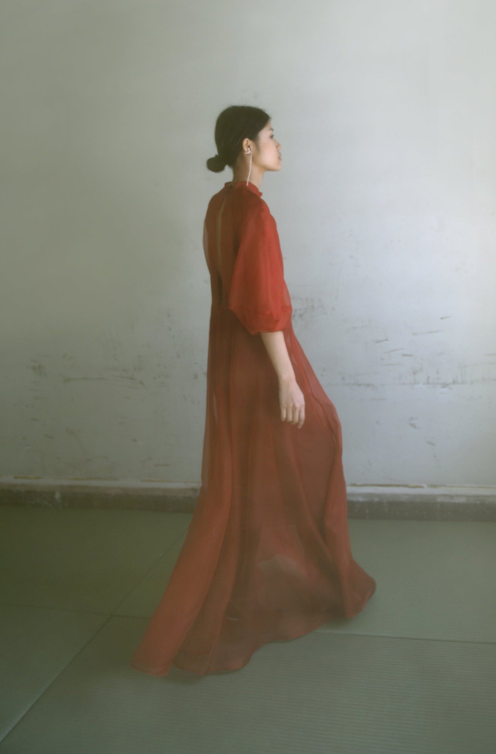 Front view of a model wearing the rust silk organza Kamperett Meiere Gown, with architectural sleeves and fitted waist.