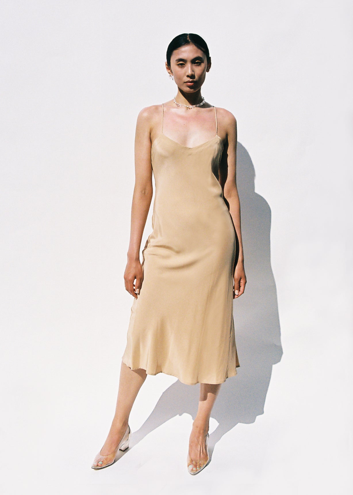 Front view of a model wearing the buff silk Kamperett V-Neck Midi Slip, a bias-cut mid-calf slip with V-neckline.