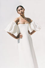 Editorial film image of a bride wearing the alabaster silk crepe Kamperett Verona Gown, an off-shoulder maxi with detachable draped sleeves.
