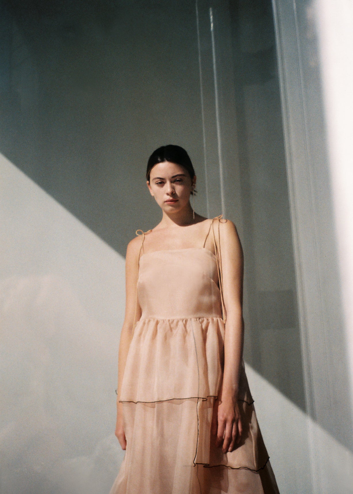 Side view of the blush silk organza Kamperett Laurence Midi Dress showing the tiered panels and full skirt.