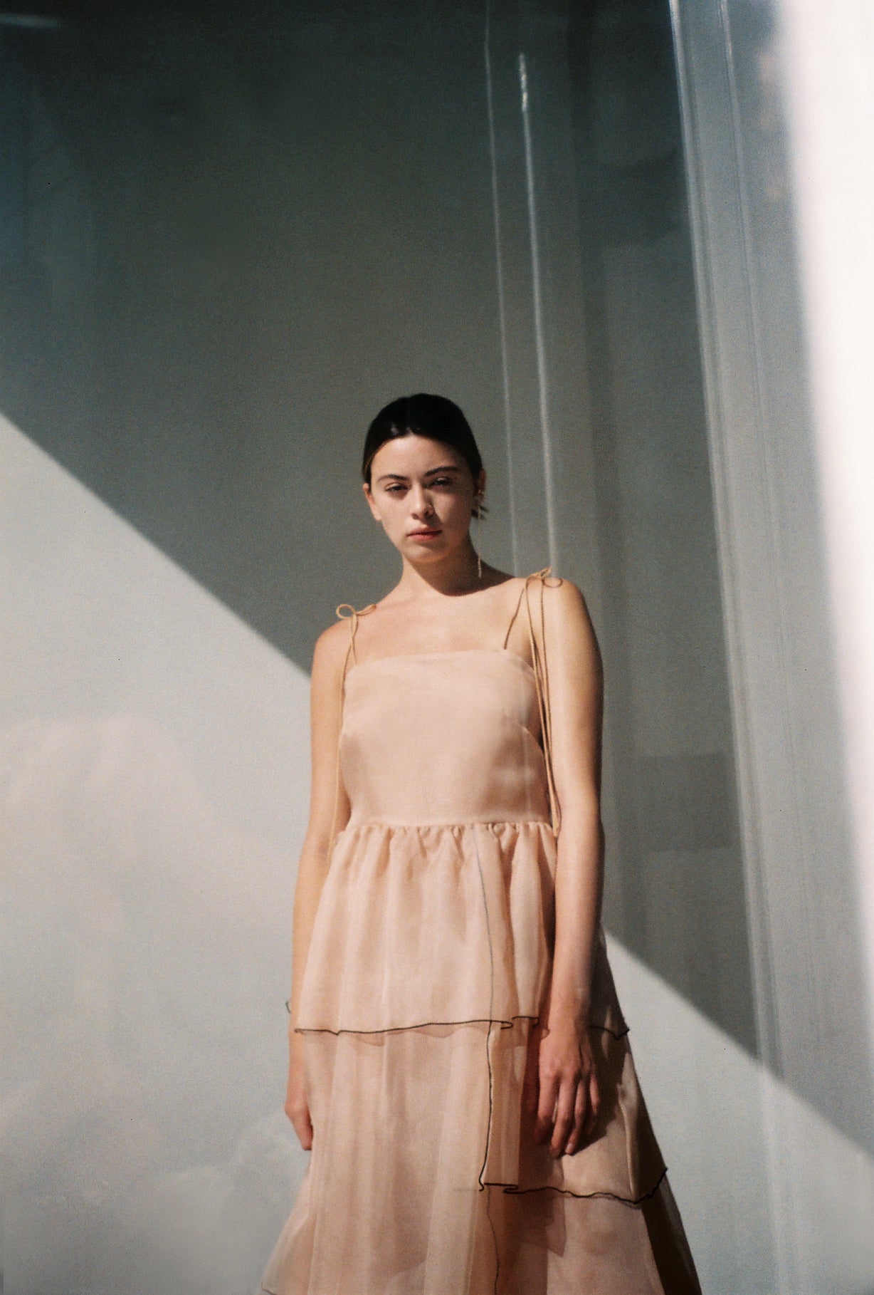 Side view of the blush silk organza Kamperett Laurence Midi Dress showing the tiered panels and full skirt.