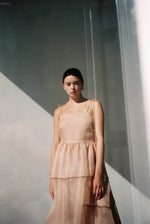 Side view of the blush silk organza Kamperett Laurence Midi Dress showing the tiered panels and full skirt.