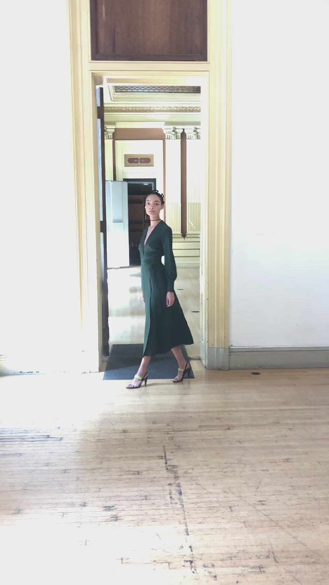Model wearing the Kamperett Adelaide Midi dress in Dark Green silk satin, featuring a plunging wrap neckline and long sleeves with wide cuffs.
