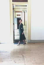 Model wearing the Kamperett Adelaide Midi dress in Dark Green silk satin, featuring a plunging wrap neckline and long sleeves with wide cuffs.